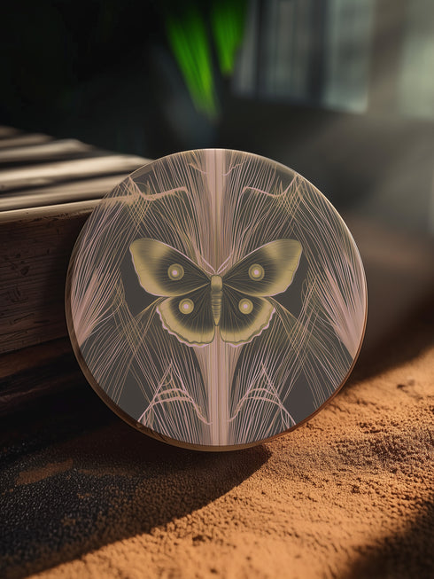 Round ceramic coaster featuring golden Luna moth illustration on dark green background with rose gold linear patterns. Cork-backed, 4-inch diameter. Perfect for vintage nature and gothic decor enthusiasts.